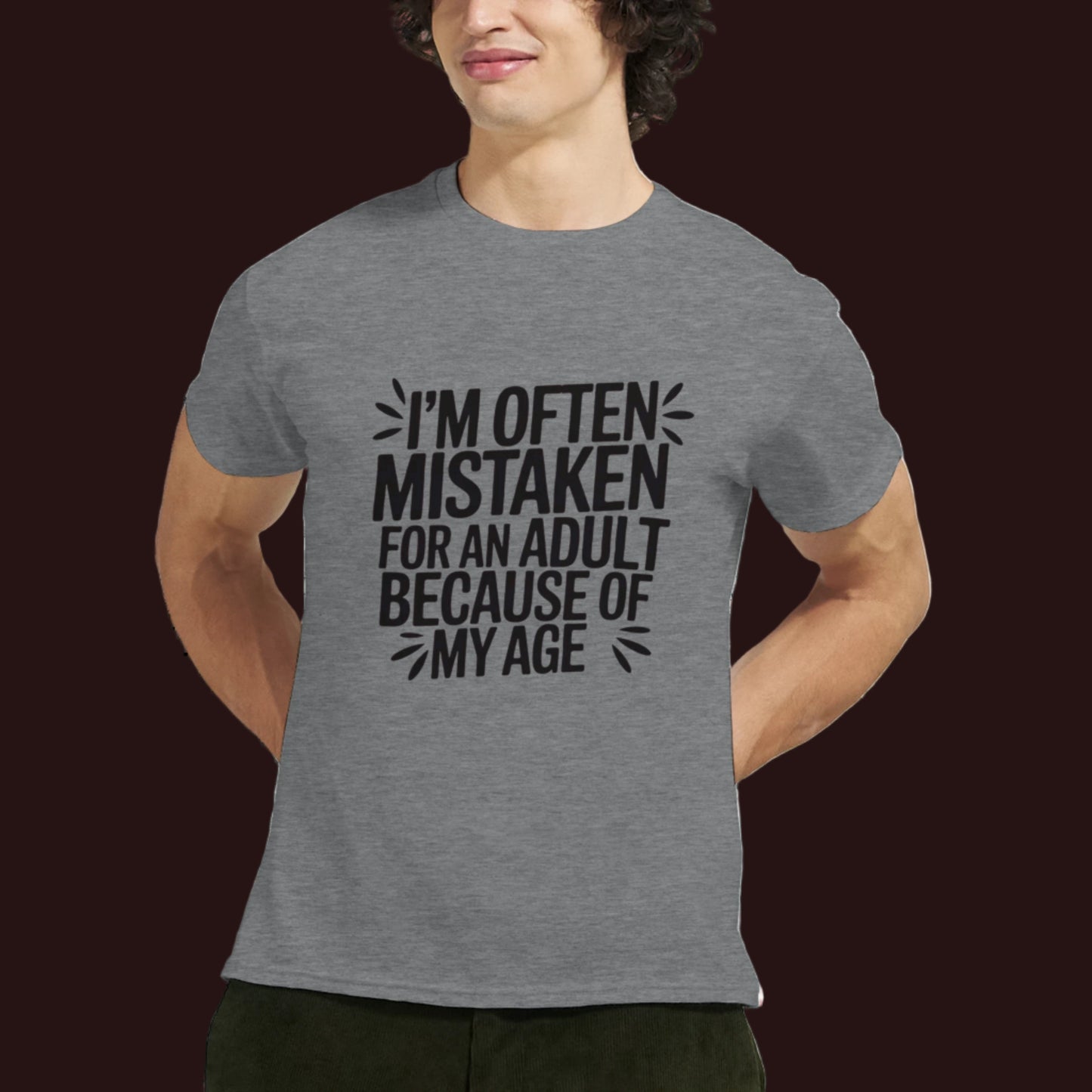 Person wearing a gray t-shirt that says "I'm often mistaken for an adult because of my age" on a white background