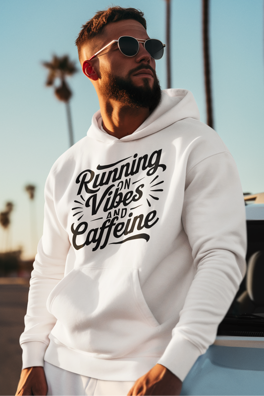 Man wearing a white hoodie that says "Running on vibes and caffeine", sunglasses, and palm trees in the background